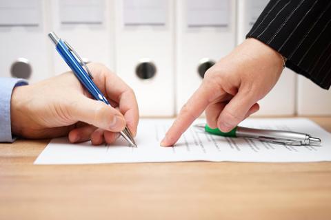Photo: Thinkstock.com. Business woman is pointing where to sign on document.